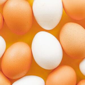 Top view of brown and white eggs arranged on a vibrant yellow surface, offering a minimalistic food pattern.
